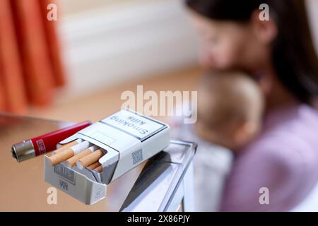 Donna che fuma accanto al neonato Foto Stock