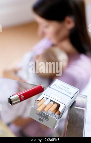 Donna che fuma accanto al neonato Foto Stock