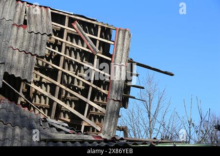 Tetto crollato in una vecchia casa a Bielsko Biala, Polonia. Rovina pericolosa con tetto in lamiera d'amianto ondulato. Foto Stock