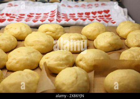 Preparare ciambelle rialzate fatte in casa con lievito - palle di impasto crude prima di friggere. Ciambelle polacche realizzate per le festività di Tlusty Czwartek (giovedì grasso) in Polonia. Foto Stock