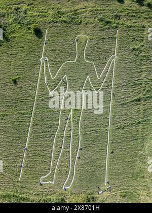 Wilmington, East Sussex, Regno Unito, 23/05/2024, Volunteers Below Paint the Long Man of Wilmington. La figura gigante sui ripidi pendii di Windover Hill è alta 72 metri e contiene due grondaie. Originariamente ritenuto neolitico, si pensa che sia ora del XVI o XVII secolo. La riverniciatura è il finale di una campagna di raccolta fondi a sostegno del lavoro della Sussex Archaeology Society (commerciale come Sussex Past), che possiede e si prende cura dell’iconica figura collinare nota come «The Guardian of the South Downs». La campagna ha raccolto oltre 10.000 sterline e ha visto quasi 300 donatori pagare 30,00 sterline per adottare uno dei 770 blocchi Foto Stock