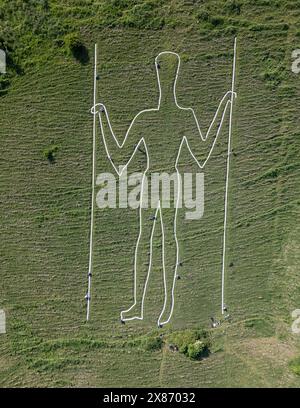 Wilmington, East Sussex, Regno Unito, 23/05/2024, Volunteers Below Paint the Long Man of Wilmington. La figura gigante sui ripidi pendii di Windover Hill è alta 72 metri e contiene due grondaie. Originariamente ritenuto neolitico, si pensa che sia ora del XVI o XVII secolo. La riverniciatura è il finale di una campagna di raccolta fondi a sostegno del lavoro della Sussex Archaeology Society (commerciale come Sussex Past), che possiede e si prende cura dell’iconica figura collinare nota come «The Guardian of the South Downs». La campagna ha raccolto oltre 10.000 sterline e ha visto quasi 300 donatori pagare 30,00 sterline per adottare uno dei 770 blocchi Foto Stock