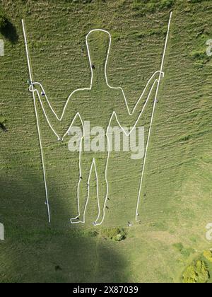 Wilmington, East Sussex, Regno Unito, 23/05/2024, Volunteers Below Paint the Long Man of Wilmington. La figura gigante sui ripidi pendii di Windover Hill è alta 72 metri e contiene due grondaie. Originariamente ritenuto neolitico, si pensa che sia ora del XVI o XVII secolo. La riverniciatura è il finale di una campagna di raccolta fondi a sostegno del lavoro della Sussex Archaeology Society (commerciale come Sussex Past), che possiede e si prende cura dell’iconica figura collinare nota come «The Guardian of the South Downs». La campagna ha raccolto oltre 10.000 sterline e ha visto quasi 300 donatori pagare 30,00 sterline per adottare uno dei 770 blocchi Foto Stock