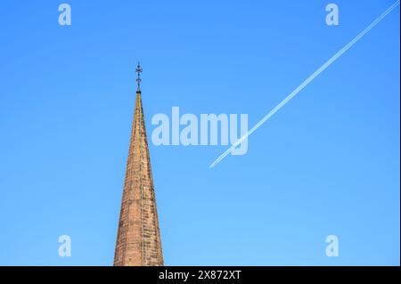 Campanile della chiesa con una pista di vapore aeroplano sullo sfondo Foto Stock