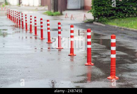 Segnaletica stradale, pedane in plastica flessibili con segnaletica bianca per pedoni e segnaletica con freccia sul pavimento in cemento nell'area parcheggio Foto Stock