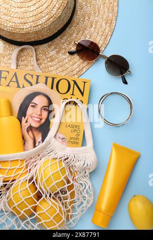 Borsa a cordoncino con rivista, limoni e accessori estivi su sfondo azzurro, piatto Foto Stock