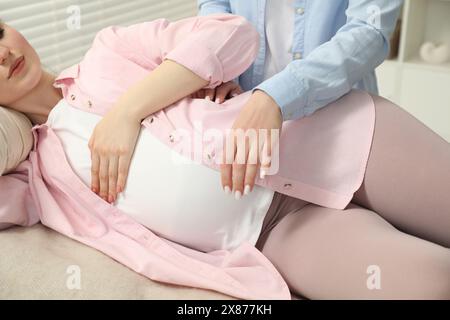 Doula si prende cura di donne incinte al chiuso, primo piano. Preparazione alla nascita del bambino Foto Stock