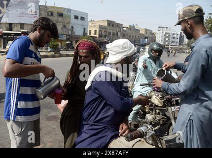 Le persone si stanno dissetando dall'acqua fredda per sconfiggere il caldo del sole rovente durante il caldo della stagione estiva organizzato dagli assistenti sociali, nella zona di Guru Mandir a Karachi giovedì 23 maggio 2024. Foto Stock