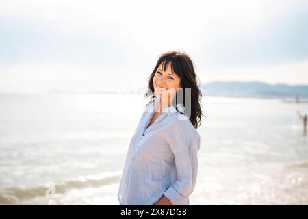 Donna sorridente che trascorre il tempo libero in spiaggia Foto Stock