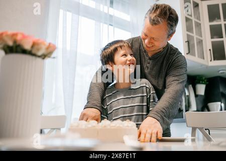 Padre e figlio festeggiano il compleanno in cucina a casa Foto Stock