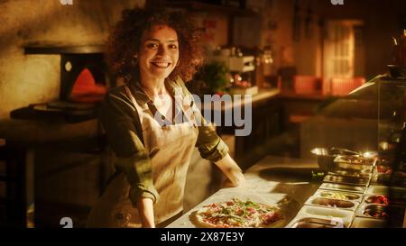 Nel ristorante Ritratto di chef professionista che finiscono di preparare la pizza, guardando la macchina fotografica con un sorriso. Tradizionale famiglia Italiana, ricetta. Autentica pizzeria soleggiata, cucina deliziosi piatti biologici Foto Stock