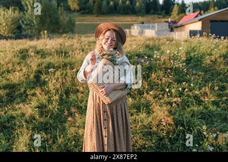 Donna felice che tiene un cestino di fiori sul campo Foto Stock