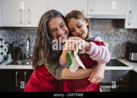 Nonna felice che abbraccia la nipote in cucina a casa Foto Stock