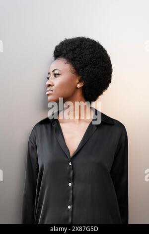 Donna afro premurosa in piedi vicino al muro Foto Stock