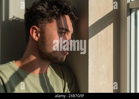 Un giovane premuroso che guarda dalla finestra Foto Stock