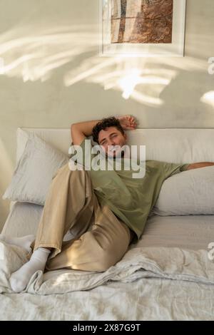 Un giovane sorridente che si rilassa a letto a casa Foto Stock