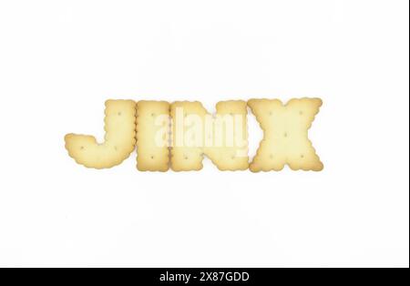 Biscotti a forma di lettera maiuscola che formano la parola JINX isolata su sfondo bianco Foto Stock