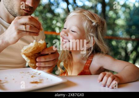 Padre e figlia mangiano croissant insieme a casa Foto Stock