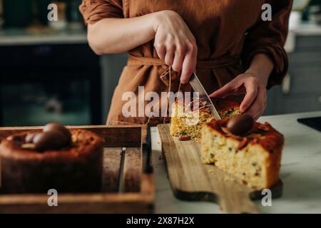 Donna che taglia la torta di Pasqua fresca in cucina Foto Stock