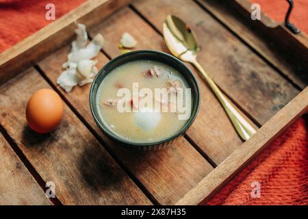 Zuppa polacca tradizionale fresca Zurek nel recipiente su vassoio di legno Foto Stock