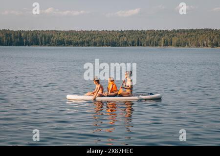 Madre con bambini paddleboard in mare Foto Stock