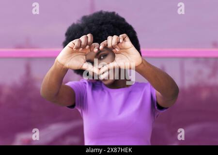 Giovane donna sorridente che mostra la forma del cuore con le mani Foto Stock