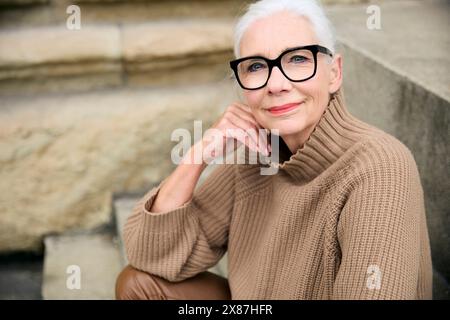 Donna anziana sorridente in maglione beige Foto Stock