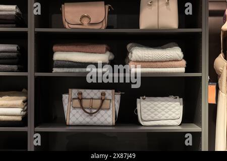 Vestiti e borse sugli scaffali Foto Stock