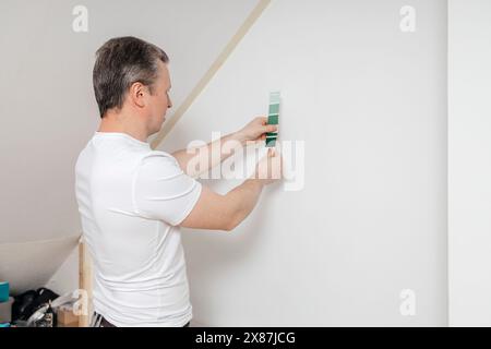 Uomo che sceglie la pittura da parete usando la colorazione a casa Foto Stock