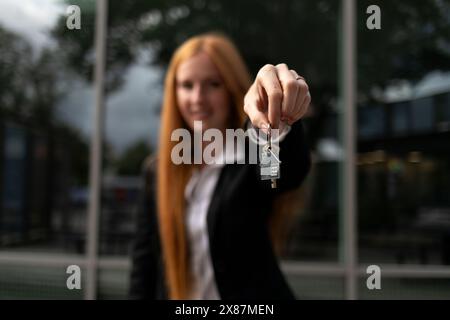 Giovane agente immobiliare che dà la chiave della casa Foto Stock