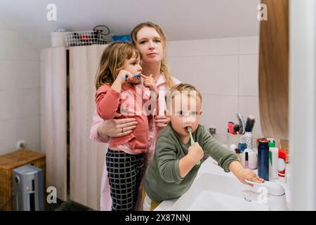 Madre con bambini che lavano i denti in bagno a casa Foto Stock