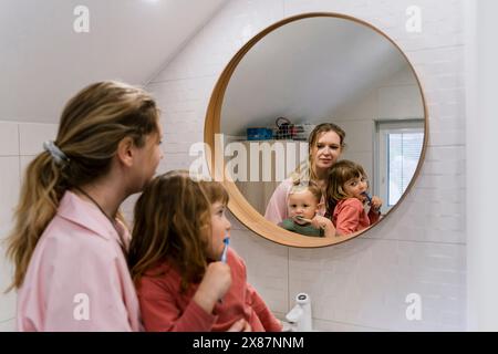 Madre con i bambini che spazzolano i denti in bagno Foto Stock