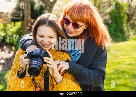 Madre e figlia sorridenti che guardano la macchina fotografica nel parco Foto Stock