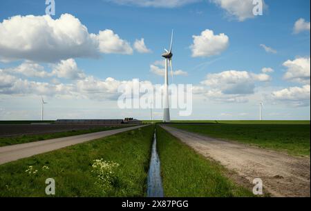 Il flusso d'acqua tra l'erba e le turbine eoliche Foto Stock