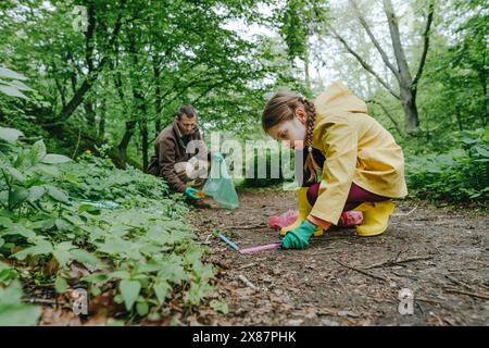 Padre e figlia raccolgono rifiuti di plastica nella foresta Foto Stock