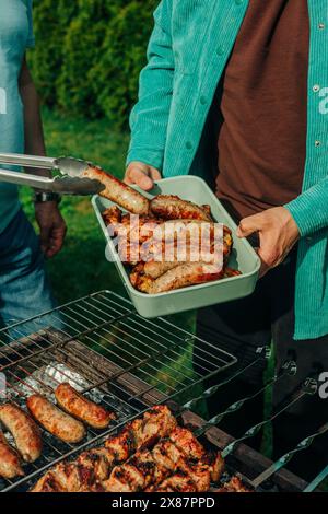 Uomini che preparano salsicce al barbecue Foto Stock