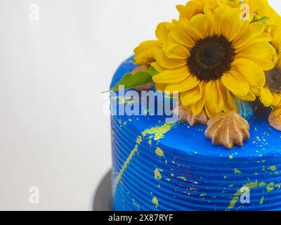 Splendida torta adornata con girasoli freschi e glassa blu vivace, perfetta per le celebrazioni e per aggiungere un tocco di colore a qualsiasi evento Foto Stock