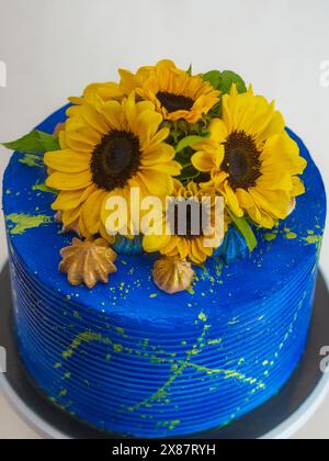 Splendida torta adornata con girasoli freschi e glassa blu vivace, perfetta per le celebrazioni e per aggiungere un tocco di colore a qualsiasi evento Foto Stock