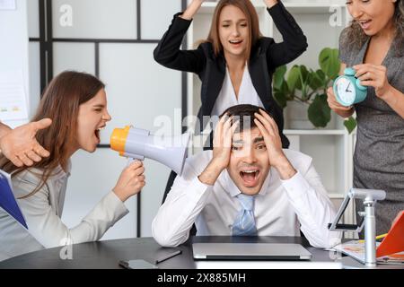 Uomo d'affari maturo che soffre di colleghi rumorosi in ufficio Foto Stock