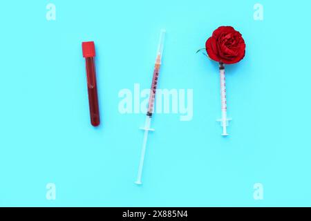 Siringhe mediche e provetta con sangue su sfondo blu Foto Stock
