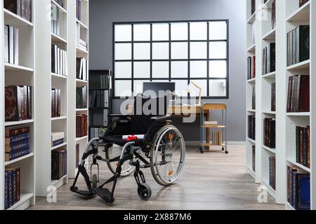 Sedia a rotelle con diploma e cappello di laurea in biblioteca Foto Stock