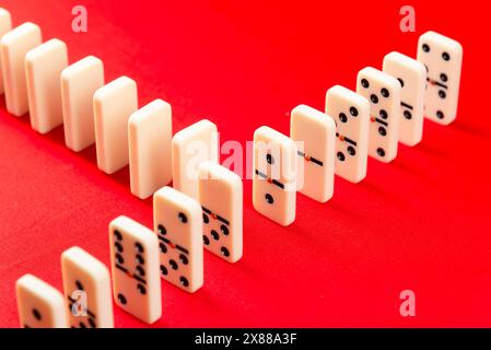 Effetto domino pronto per iniziare. Pezzi acrilici di fila. Isolato su sfondo rosso. Foto Stock