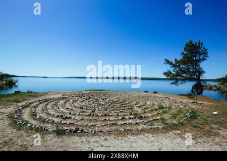 Labirinto a spirale fatto di pietre sulla costa. Foto Stock