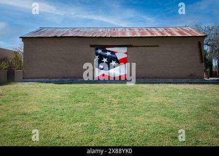 Un albergo verde con un vecchio edificio in mattoni con un tetto in stagno arrugginito che mostra un pezzo della bandiera americana, un dettaglio in rosso, bianco e blu Foto Stock