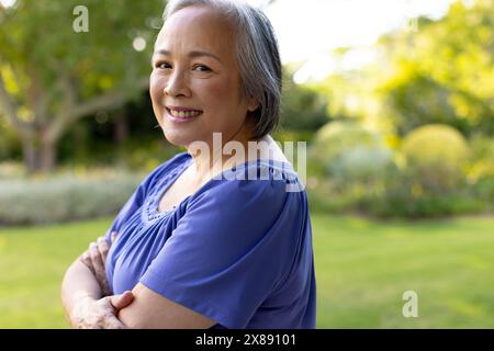 Una donna asiatica di mezza età con i capelli grigi corti sorride all'aperto Foto Stock