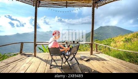 Sulla cima della montagna nel comune di DAC Loc, Nha Trang, Vietnam - 17 maggio 2024: Turista femminile e cane Chihuahua accolgono l'alba sull'alto mou Foto Stock