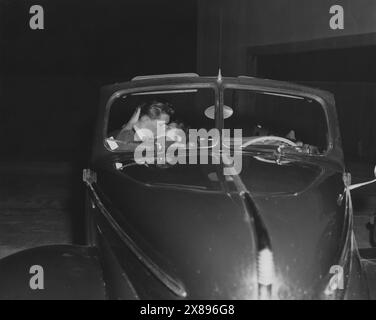 Giovane coppia in cabriolet che si esibisce in un drive-in negli anni '1930 Foto Stock