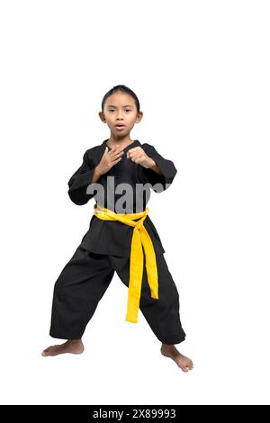 Giovane ragazza sicura di sé che dimostra una posizione di combattimento di karate. Indossare un'uniforme nera con una cintura gialla. Isolato su sfondo bianco Foto Stock