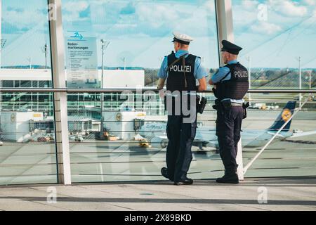 Due agenti armati di polizia aeroportuale che sorvegliano una via di rullaggio all'aeroporto di Monaco, in Germania, dalla piattaforma di osservazione esterna del Terminal 2 Foto Stock