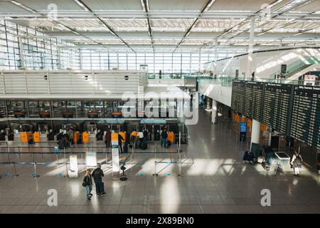 Un'area check-in vuota al Terminal 2 dell'Aeroporto Internazionale di Monaco, in Germania, in un pomeriggio tranquillo. Le pareti delle finestre lasciano entrare molta luce naturale Foto Stock